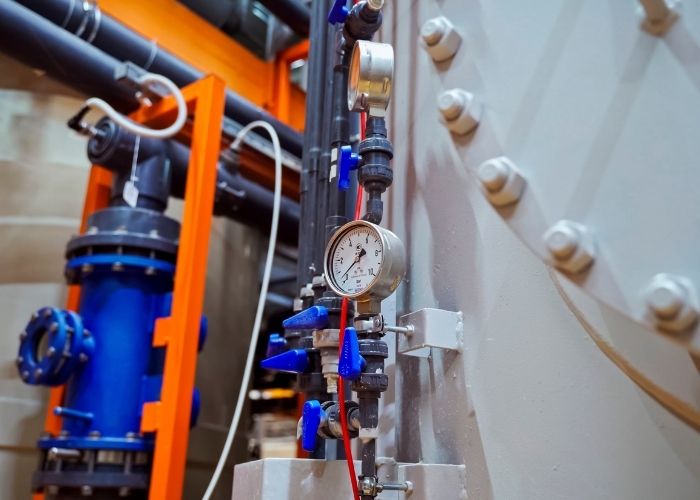 Hydraulic pressure gauge connected to industrial machinery, showing pressure measurement in a hydraulic system.