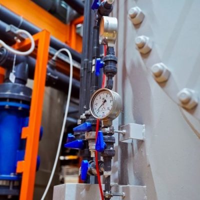 Hydraulic pressure gauge connected to industrial machinery, showing pressure measurement in a hydraulic system.